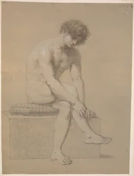 Modelo sentado en un pedestal bajo con cojín. Girado hacia la derecha. Brazos colgando. Piernas cruzadas