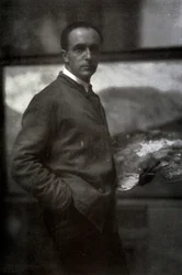 Retrato de tres cuartos de Cesare Maggi. El pintor, vestido con una bata, sostiene una paleta en su mano izquierda. En el fondo, la lona en la que está trabajando