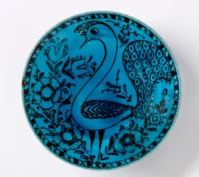 Un plato de cerámica persa del siglo XIX que representa un pavo real sobre fondo turquesa