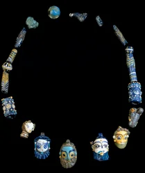 Collar de pasta de vidrio con colgantes que representan cabezas barbadas, procedente originalmente de Olbia y conservado actualmente en el Museo Arqueológico Nacional de Cagliari