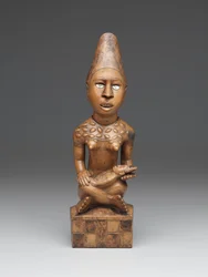 Figura femenina sentada con niño (pfemba) Grupo Yombe, Pueblos Kongo (madera, vidrio o mica y tinte)