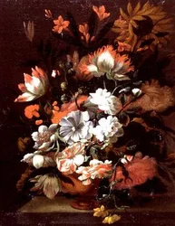 Tulipanes, claveles, girasoles y otras flores en una urna sobre un borde de piedra