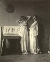 Dos modelos femeninas en traje clásico con la escultura 