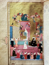 El Profeta Mahoma (Muhammad) (570-632) (rostro cubierto) durante el Mirac, su ascenso al séptimo cielo. Miniatura del manuscrito “Zubdat al-Tawarikh” por el historiador Seyyid Loqman Ashuri bajo el reinado de Murad III