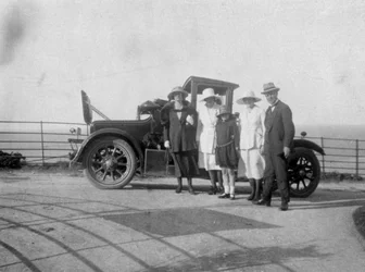Un grupo de personas frente a su coche en la playa, c1920s