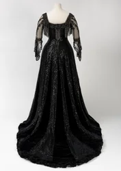 Vestido de noche negro largo usado por la reina Alexandra, con decoración de cuentas y lentejuelas e incorporando la característica cinta de seda negra con el nombre en letras doradas de la reina Alexandra, realizado por Barolet of Knightsbridge, Londres