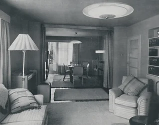 Comedor y sala de estar, divididos solo por cortinas pesadas en un tejido moderno atractivo, 1942