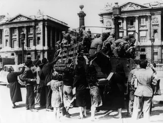 Vendedores callejeros franceses ofreciendo souvenirs a un camión lleno de soldados alemanes, París, 27 de julio de 1940