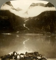 Glaciar Grytereids brillando sobre nubes flotantes, sobre el tranquilo Lago Olden, Noruega, c. 1905