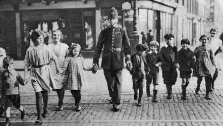 Policía ayudando a los escolares a cruzar la calle, East End, Londres, 1926-1927