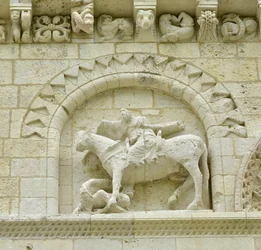 Arte románico: detalle de la fachada que representa a Hugues de Surgeres y Geoffroy de Vendome o al emperador Constantino I el Grande cuyo pie del caballo pisaría la herejía y Cristo triunfante del mal y la muerte, Notre Dame de Surgeres