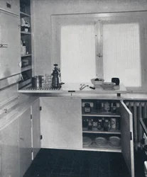 Werner Harting - Cocina con suelo de baldosas negras holandesas, paredes blancas y estantes y armarios empotrados