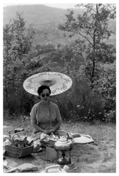Mujer bajo una sombrilla haciendo un picnic, c1950-1969