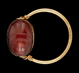 Escarabajo de cornalina con cara humana engastado en un anillo de oro
