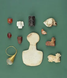 Colección de objetos del Mediterráneo Oriental incluyendo un amuleto de buitre sumerio, un sello de serpentina acadio y una rana de cornalina mesopotámica, que datan de 3300-2000 a.C.