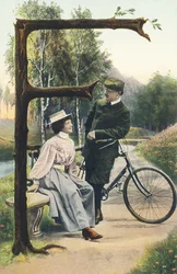 F: Un hombre en atuendo de ciclista apoyado en su bicicleta conversa con una mujer sentada en un banco. Decorado campestre - Alphabet personajes Ref Th. E., L. Theochrom - Serie 994. Theodor Eisman, editor, Leipzig