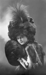 Moda: una mujer joven en piel (abrigo, sombrero de plumas y manga). Annees 1920-1930 Fotografía histórica de moda, modelo femenina.