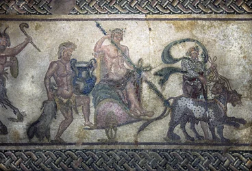 Arte romano: el triunfo de Dionisio (Baco). El dios subido en un tanque en el centro. Lleva una corona de laurel y sostiene un tirso (lanza rodeada de hiedra con una piña en el extremo). Dos panteras avanzan frente a él. Detrás del tanque, un