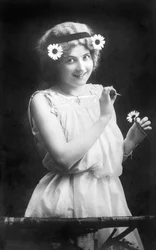 Mujer arrancando pétalos de una flor: "Me quiere. No me quiere. Me quiere..." Fotografía alrededor de 1912