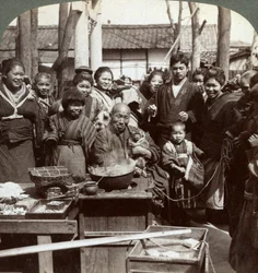 Un artista callejero con un mono divirtiendo a la multitud, Kobe, Japón, 1896
