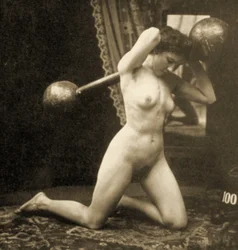 Desnudo femenino haciendo ejercicio con una barra con pesas esféricas, hacia 1900