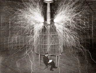 Nikola Tesla sentado en su laboratorio de Colorado Springs con su “Transmisor Magnificante”