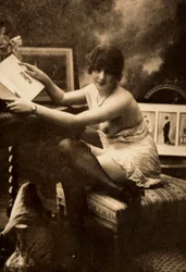 Retrato de una joven en ropa íntima, sentada a una mesa con un libro.