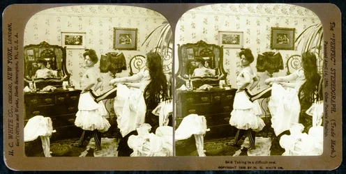 Tarjeta estereoscópica que muestra a una mujer siendo ajustada en un corsé, c.1900
