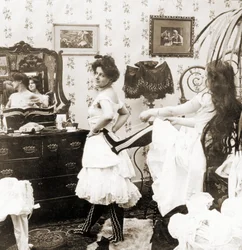 Tarjeta estereoscópica que representa a una mujer siendo ajustada en un corsé, c.1900