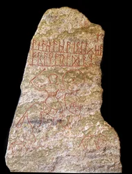 Estela con inscripciones rúnicas representando a un jinete vikingo con un perro (piedra)