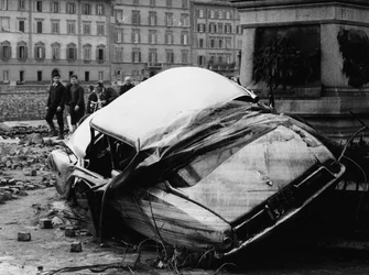 Citroen DS arrojado contra un monumento durante la inundación de Florencia, noviembre de 1966 (foto b/n)