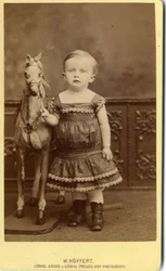 Niña de pie junto a caballo de balancín