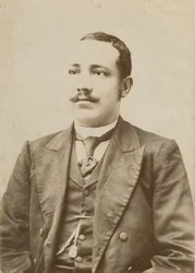 Fotografía de un hombre con traje oscuro y reloj de bolsillo en el chaleco, 1886-1900