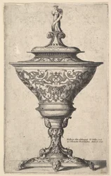 Copa ornamentada sobre pies de máscaras