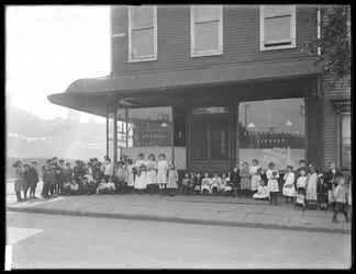 Niños posan frente a una sucursal no identificada de la Biblioteca Pública del Borough de Queens, Nueva York, c.1910