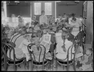 Niños leyendo en la sala de lectura de una sucursal no identificada de la Biblioteca Pública del Borough de Queens, c.1910