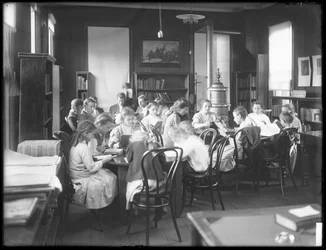 Niños leyendo en la sala de lectura de una sucursal no identificada de la Biblioteca Pública del Borough de Queens, c.1910