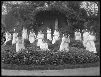 Clase graduada de niñas del Asilo de Huérfanos Católico Romano en el jardín de flores, frente a la gruta de la Virgen María, 1912