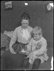 Harriet E. Hassler y William Gray Hassler, sentados con un gato atigrado (Reddy) y un oso de peluche, c.1911