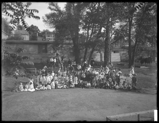 Gran grupo de niños reunidos para un retrato grupal en un patio de recreo no identificado, c.1910