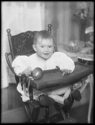 Infante no identificado sentado en una silla alta, 1915-16
