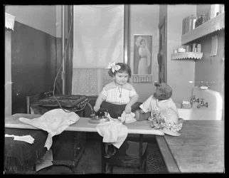Niña no identificada demostrando el uso de una plancha eléctrica, c.1913-14
