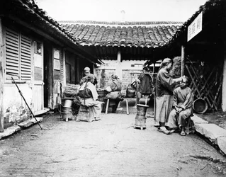 Barberos itinerantes en una casa de campo, China, c.1875