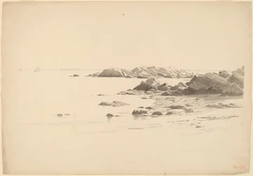 Playa rocosa con barcos distantes