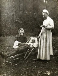 Doctor tomando el pulso a un hombre herido, asistido por una monja enfermera, circa 1900