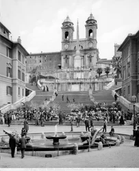 Vista de Piazza di Spagna: en primer plano está la Fontana della Barcaccia, más allá de la escalera un obelisco y la Iglesia de Trinità dei Monti.